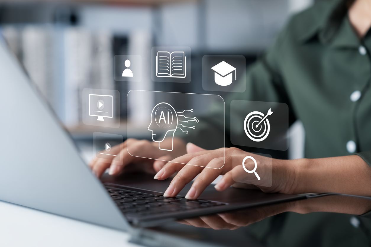 A person typing on a laptop with various digital icons overlaid, including an AI symbol, a book, a graduation cap, a target, and a magnifying glass, representing technology, education, and artificial intelligence.